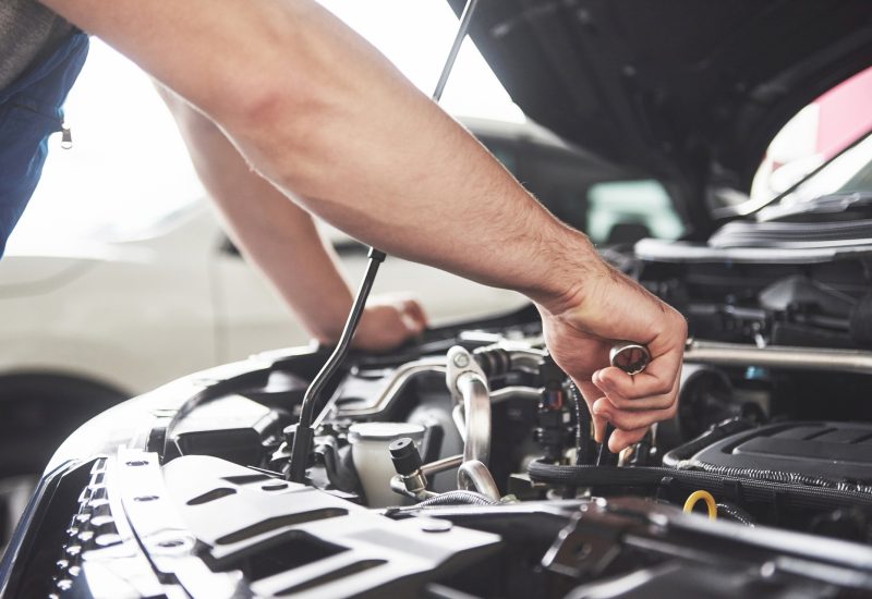 Close up hands of unrecognizable mechanic doing car service and maintenance.
