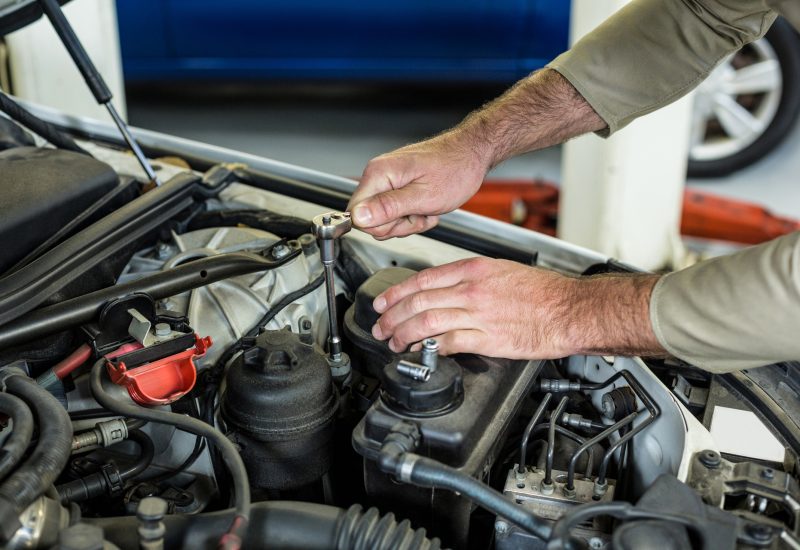 Hands of mechanic servicing a car in repair garage