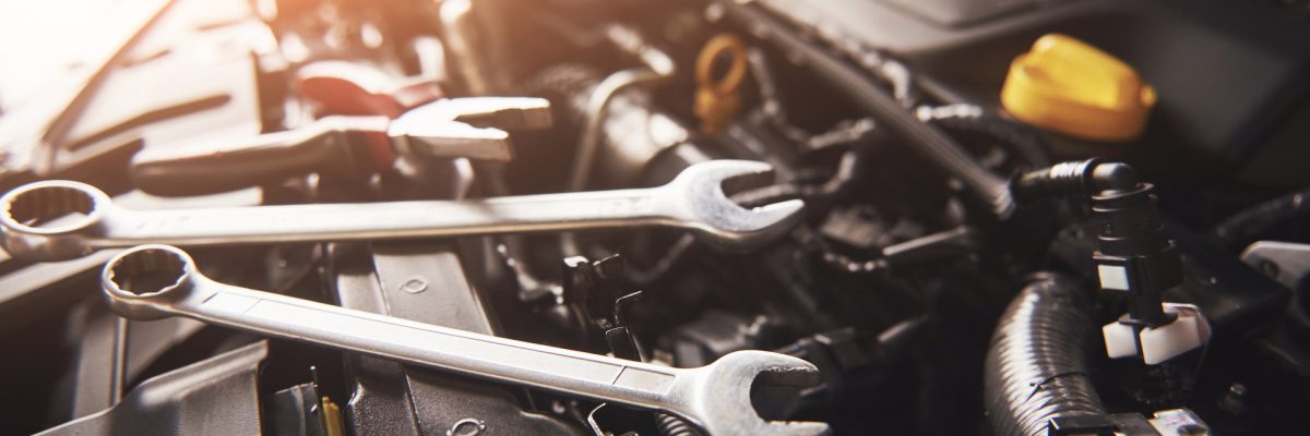 Mechanic hand checking and fixing a broken car in car service garage.